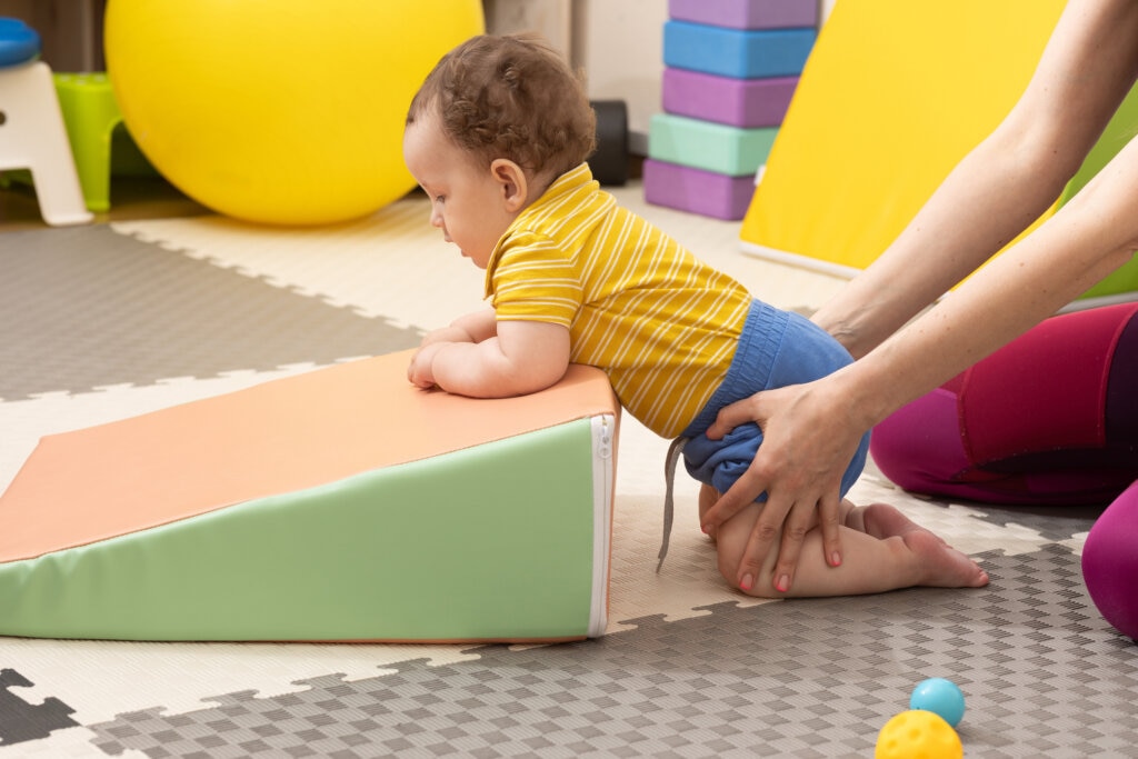 Infant physical therapy, little boy patient with muscle weakness doing treatment exercises