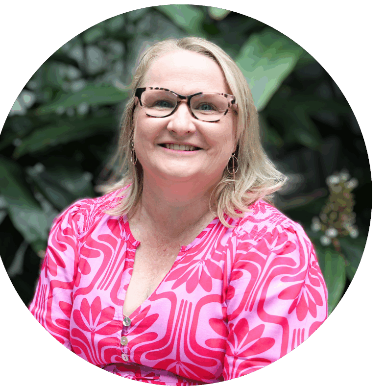 Close-up photo highlighting a woman's happy expression with eyeglasses surrounded by lush greenery